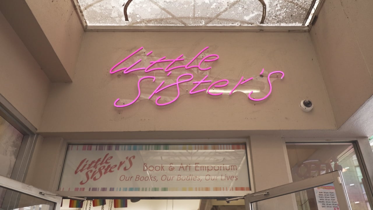 A neon sign that says "Little Sister's" in pink cursive writing.