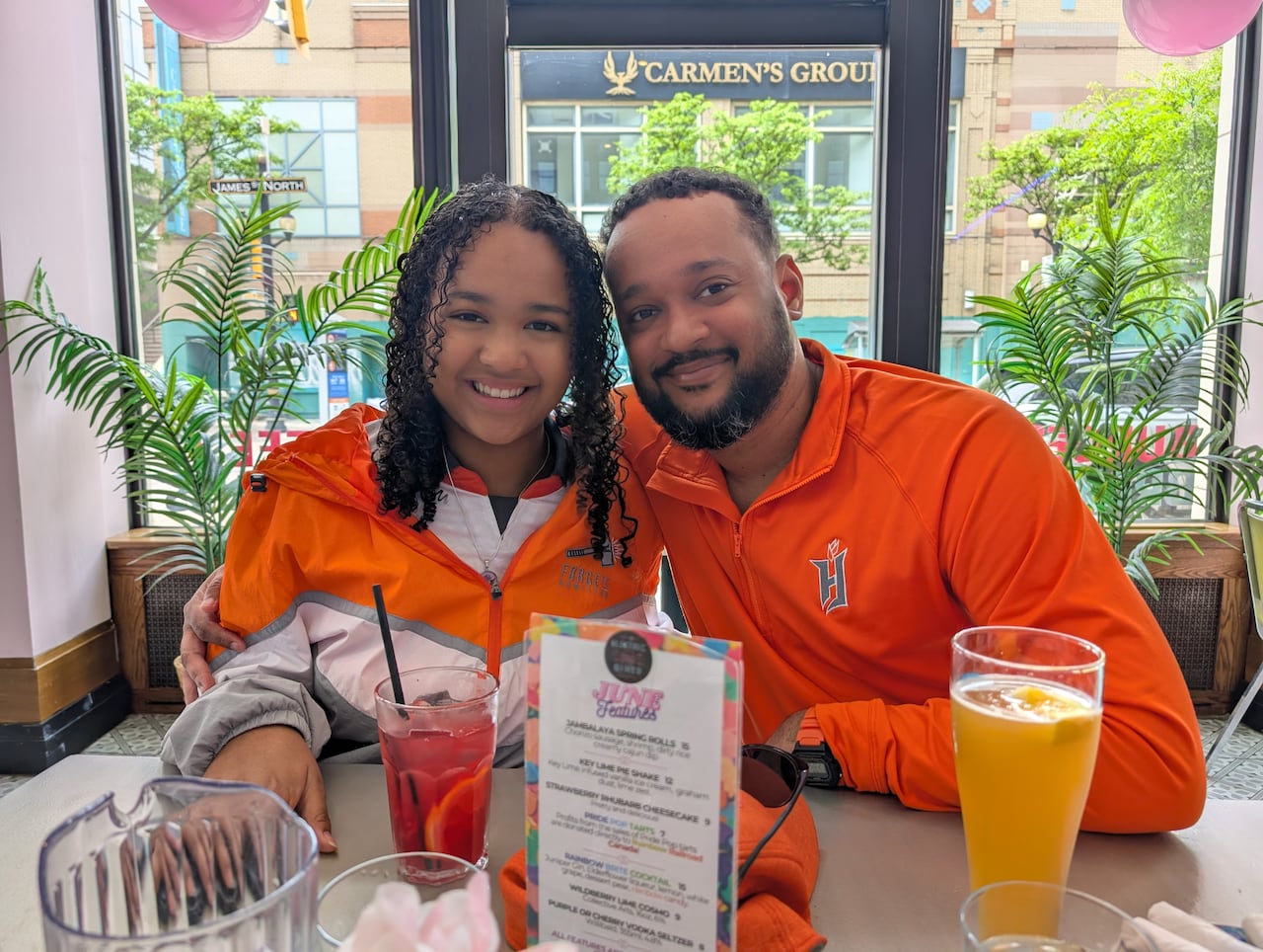 A father and daughter are wearing a lot of orange in a diner
