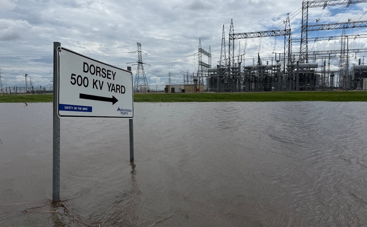 A sign with an arrow pointing left reads "Dorsey 500 KV Yard." The sign is surrounded by water and points to a power yard with electrical towers and wires