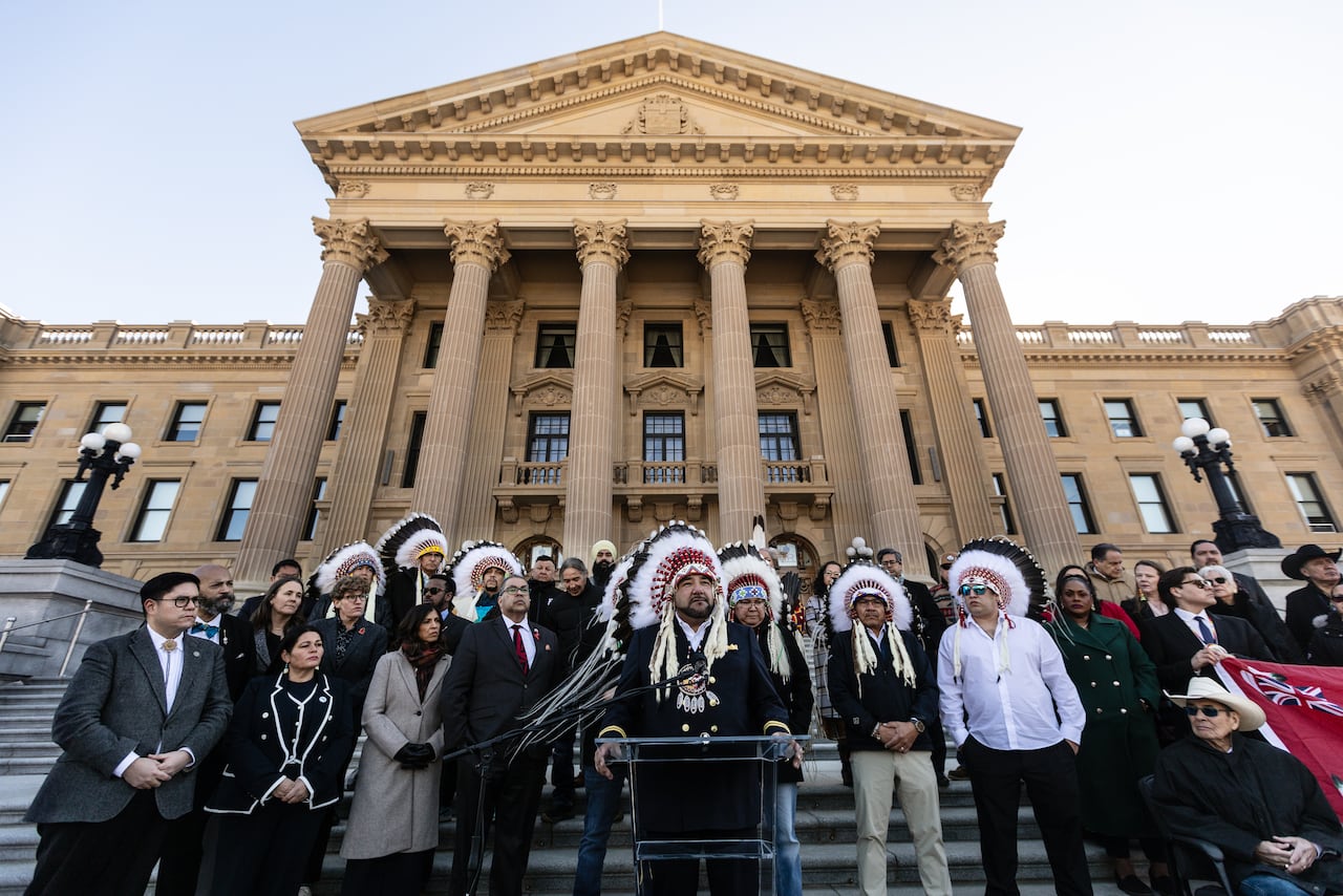 A group of people stand in front of a legislature building.