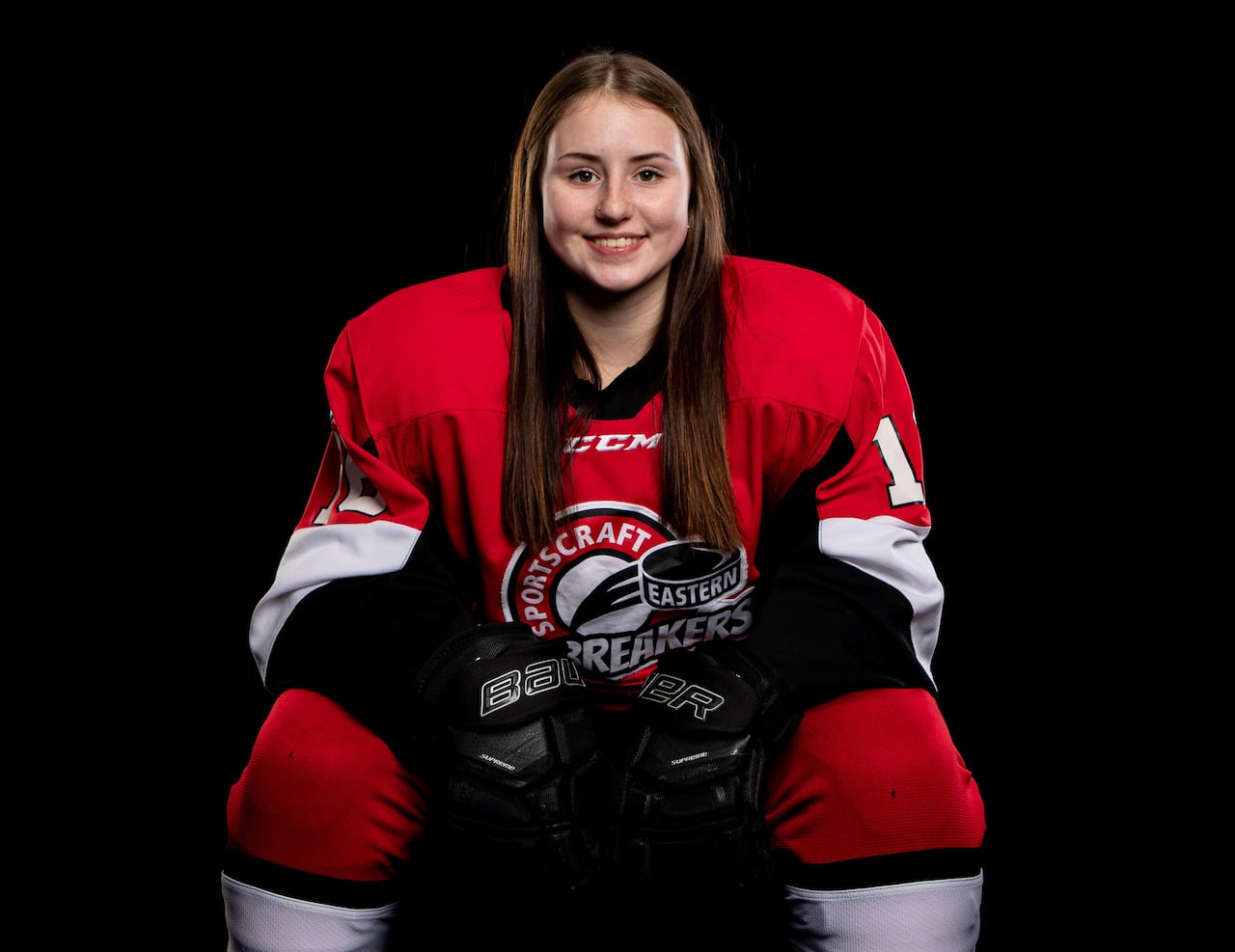 A hockey player in red jersey leaning forward against black backdrop.