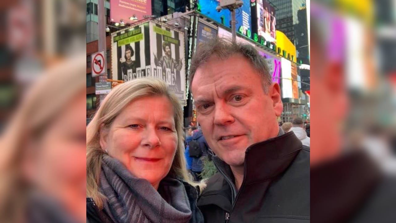 A photo of a middle-aged white couple in Times Square, used as a Facebook profile picture.