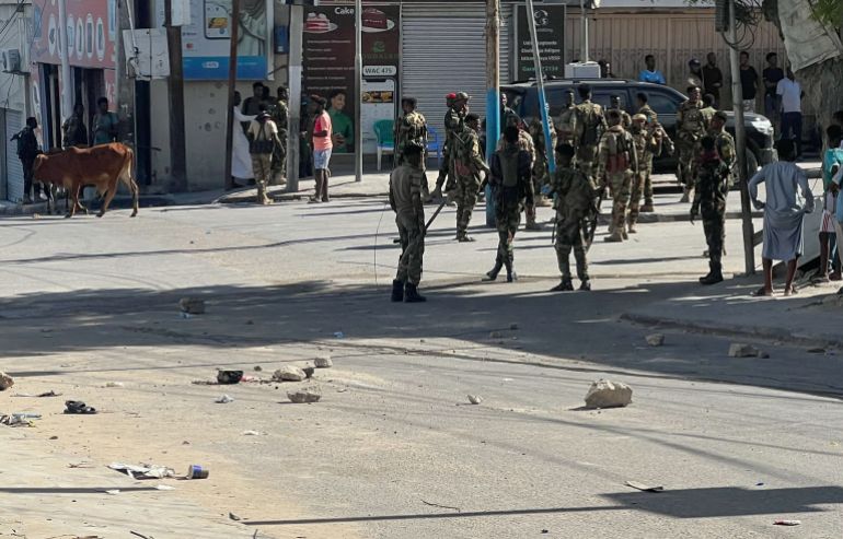 Members of Somali government forces stand among civilians at a street junction ahead of a planned protest