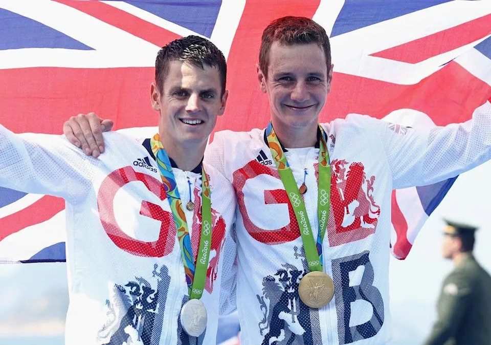 Alistair Bronwlee and Jonathan Brownlee celebrate winning a gold and silver Olympic medal respectively, holding an arm around one another and holding the Union Jack aloft in 2016.