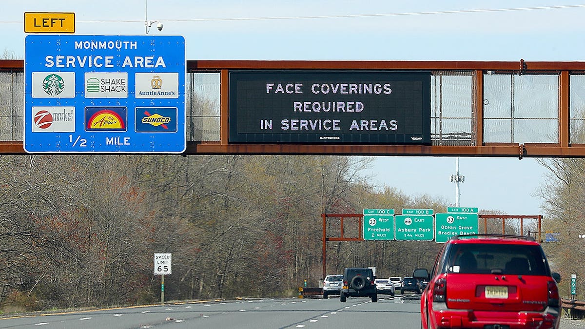 Traffic travels along the Garden State Parkway beneath an overhead sign directing motorists to the Monmouth Service Area in New Jersey