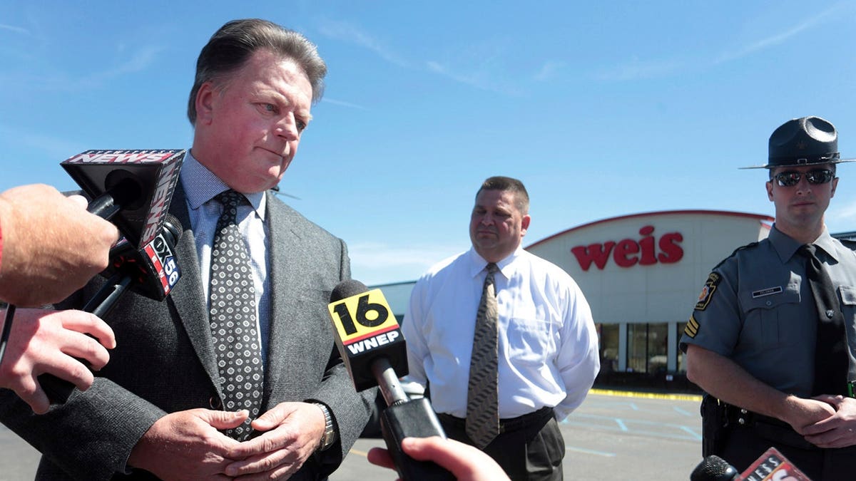 James Daly in a grey suit speaking to reporters.