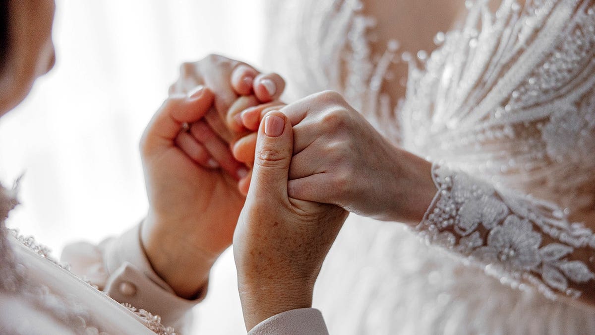 Bride tenderly holding her mother's hands