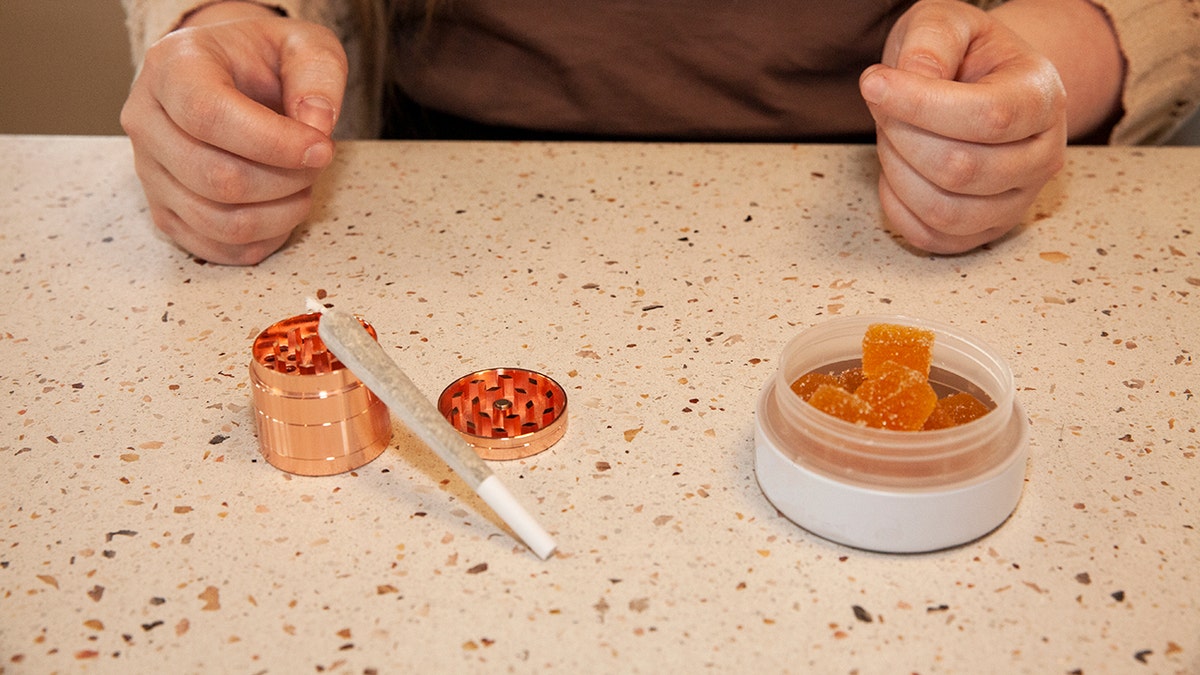 Saleswoman holding cannabis gummies and pre-rolls inside a dispensary