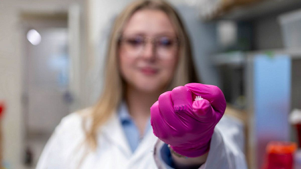 Elizabeth Kelley holding a cytokine-secreting patch in a laboratory setting