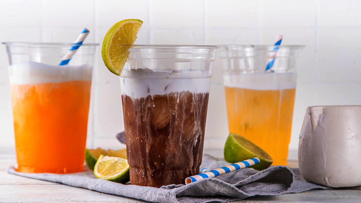 Dirty sodas in different varieties including orange and cola seen with creamer and fruit garnishes.