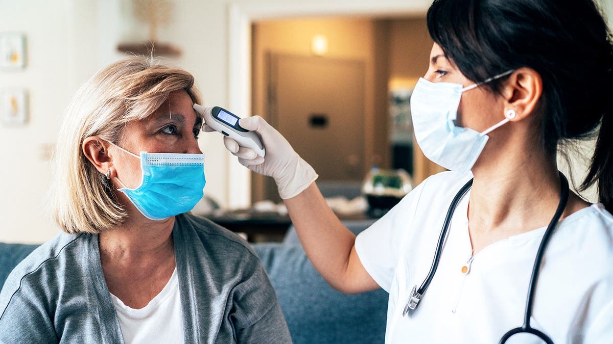A doctor takes a woman's temperature.