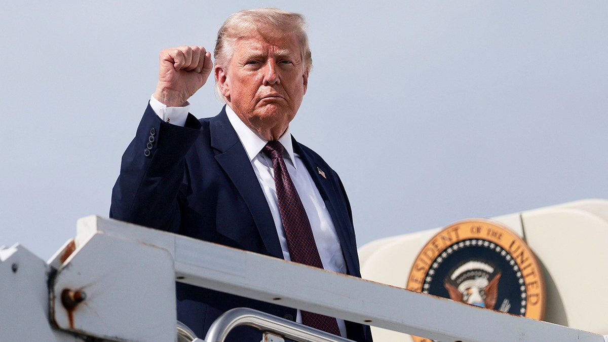 President Donald Trump raises his fist as he boards Air Force One
