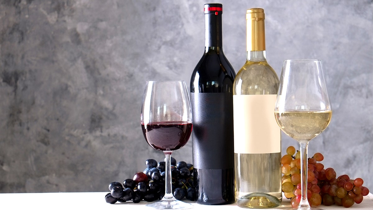Red and white wine glasses filled and placed on a wooden table.