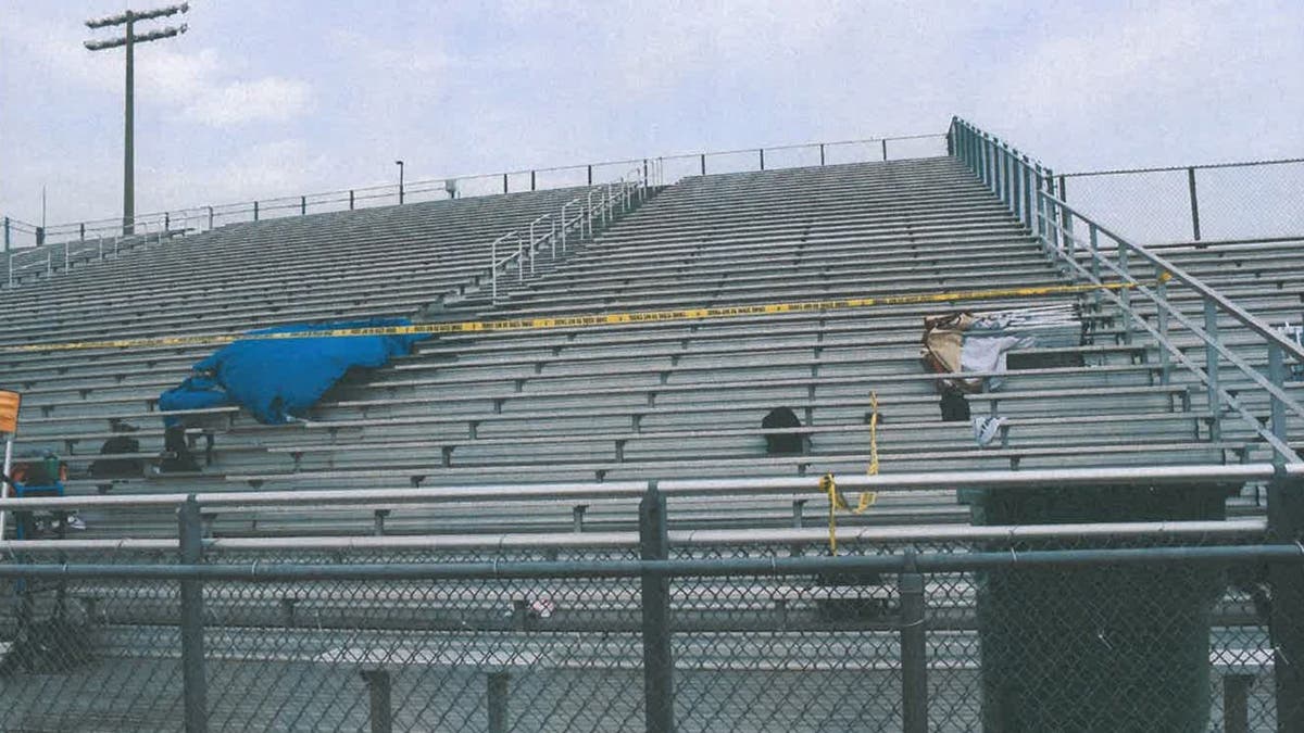 image shows bleachers and crime scene tape with a tarp