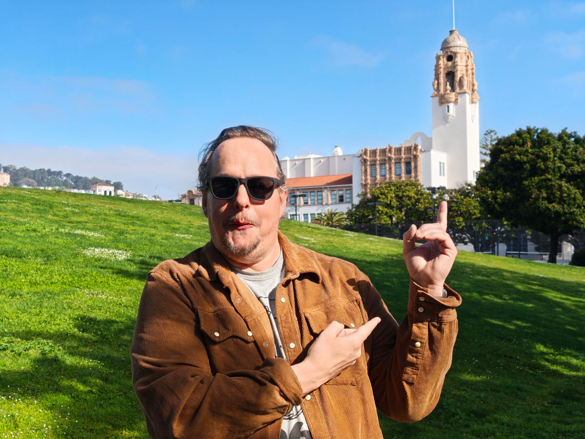 A man pointing at an old school building