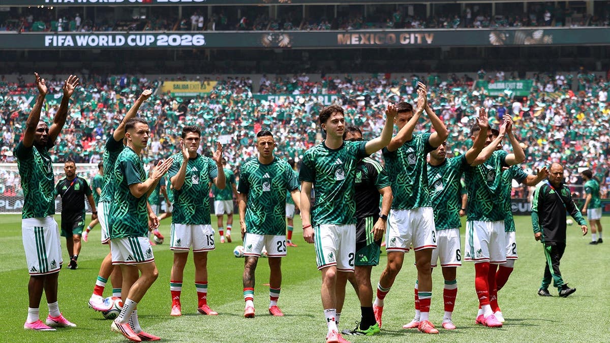 Mexico players applauding fans at Mexico City Stadium during a soccer match.