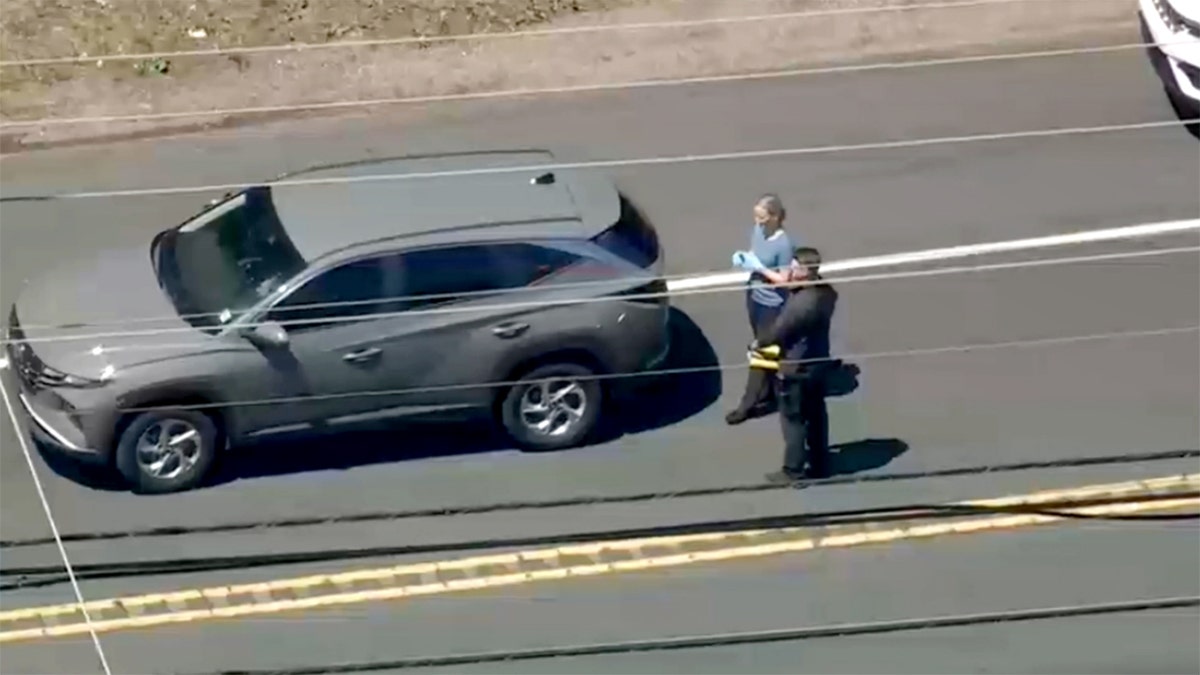Investigators standing near vehicle in the street