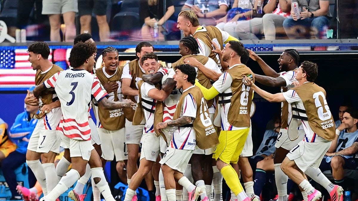 Folarin Balogun of the U.S. celebrating with teammates on soccer field.
