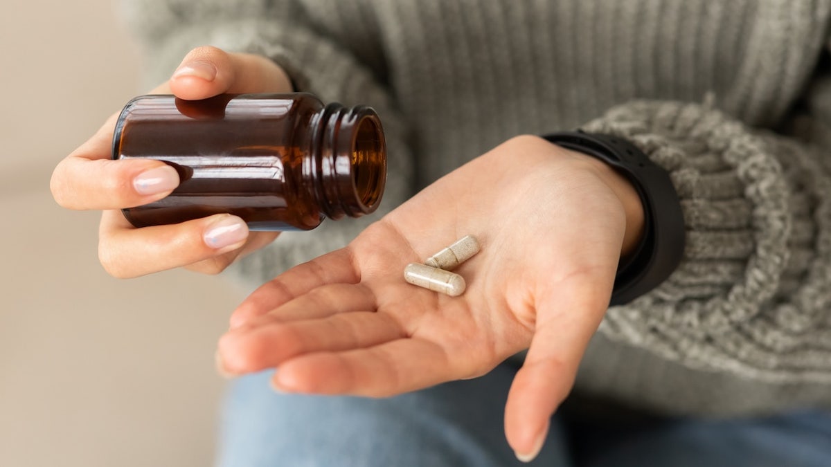 Young woman holding medicine herb capsules in her hands