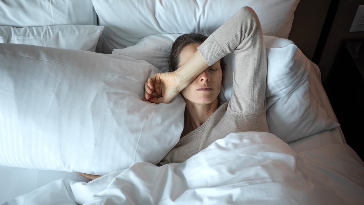 Young woman waking up in bed looking tired and suffering from insomnia