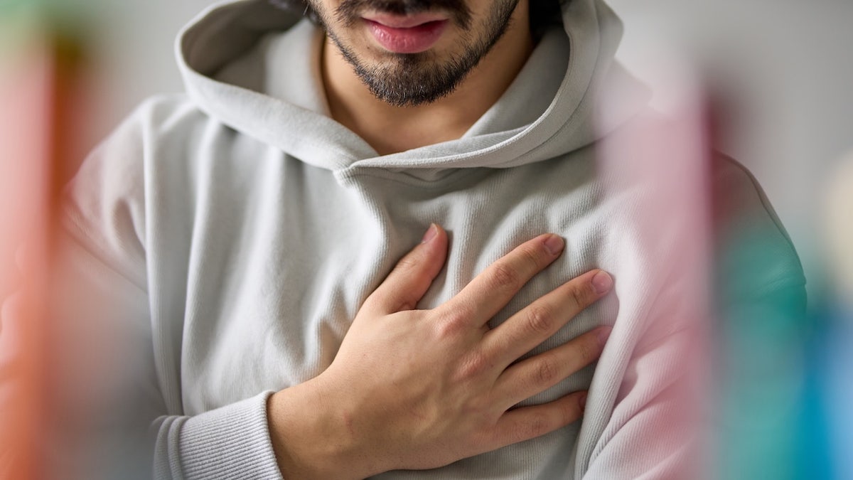 Young man holding his hand over his chest in pain