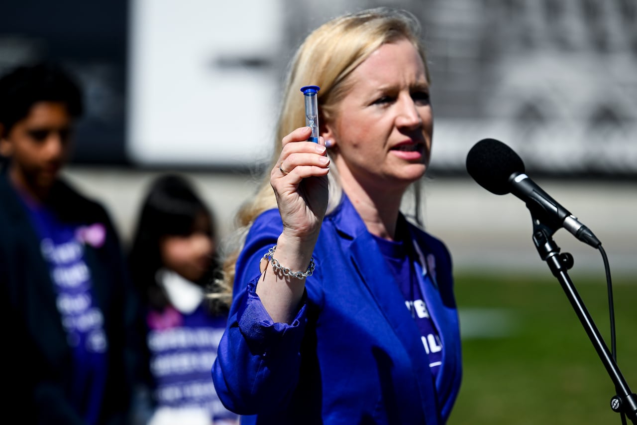 Founder and CEO of Chilholds up an hour glass as she speaks during a 'Time Is Up: Children and Families Take Over Parliament Hill to Demand Online Safety' rally on Parliament Hill in Ottawa, on Monday, April 27, 2026.