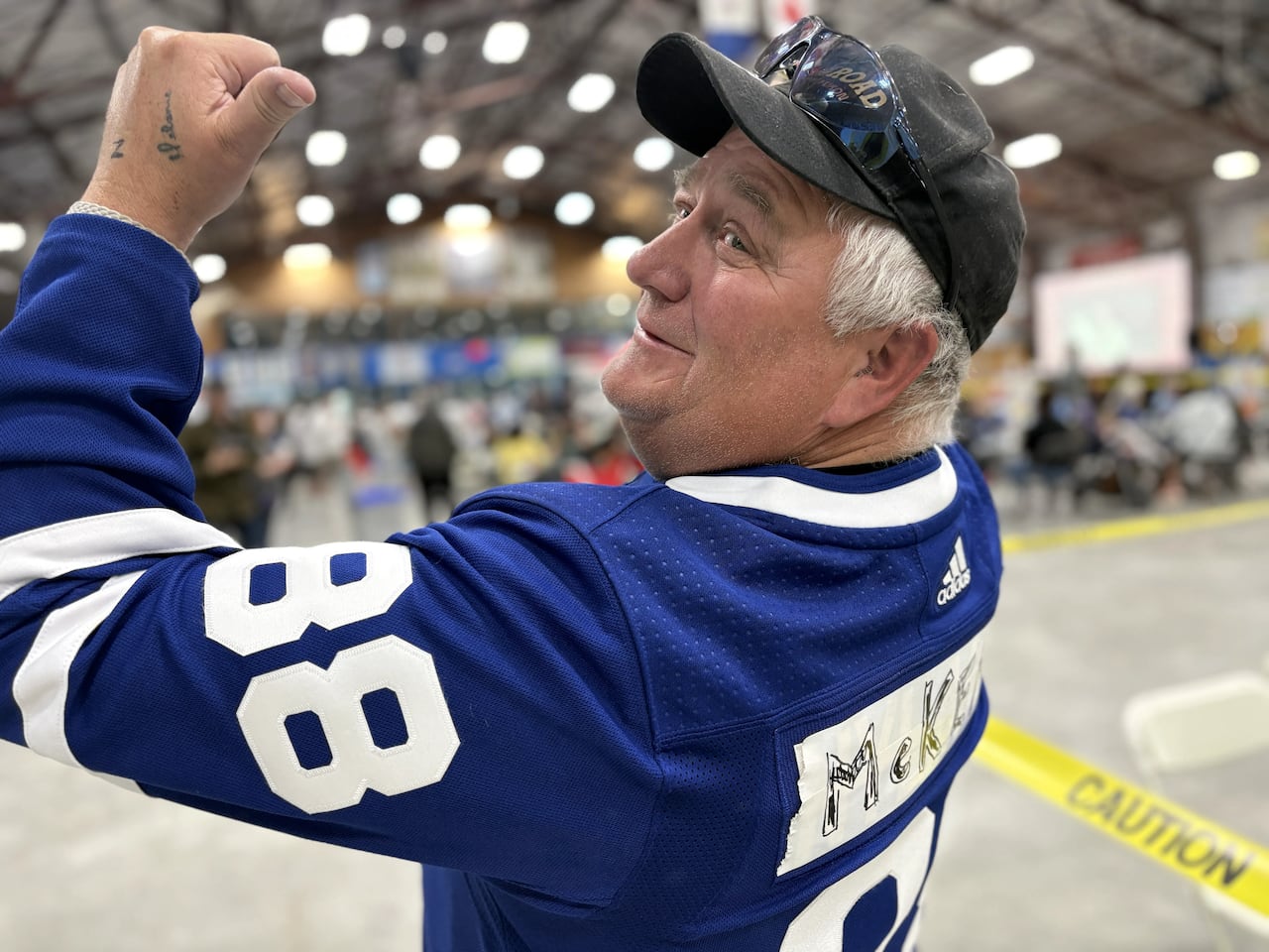 A man points to a homemade 'McKenna' label on the back of his hockey jersey.