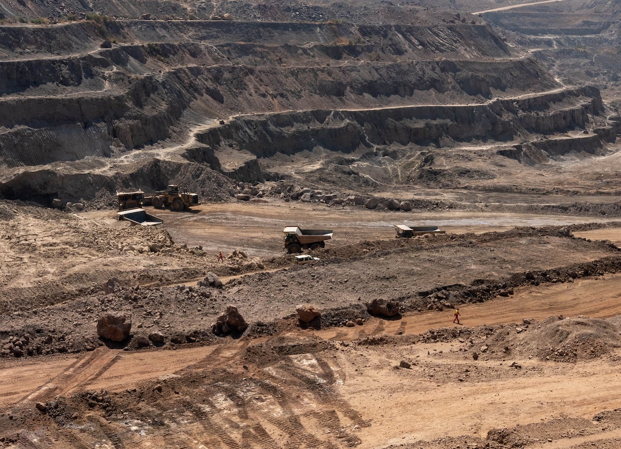 Dump trucks driving along dirt roads in a mine.