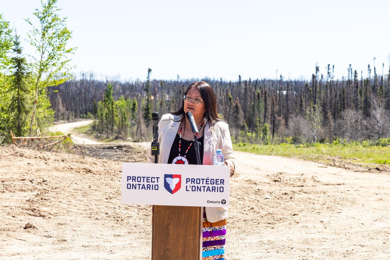 A person is seen speaking behind a podium.
