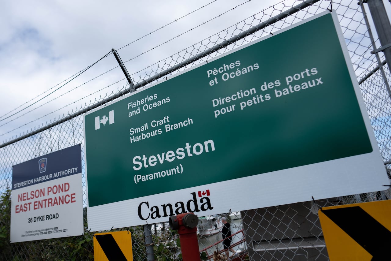 A large green sign on a fence reads 'Fisheries and Oceans,' 'Small Craft Harbours Branch,' and 'Steveston', as well as their French translations.