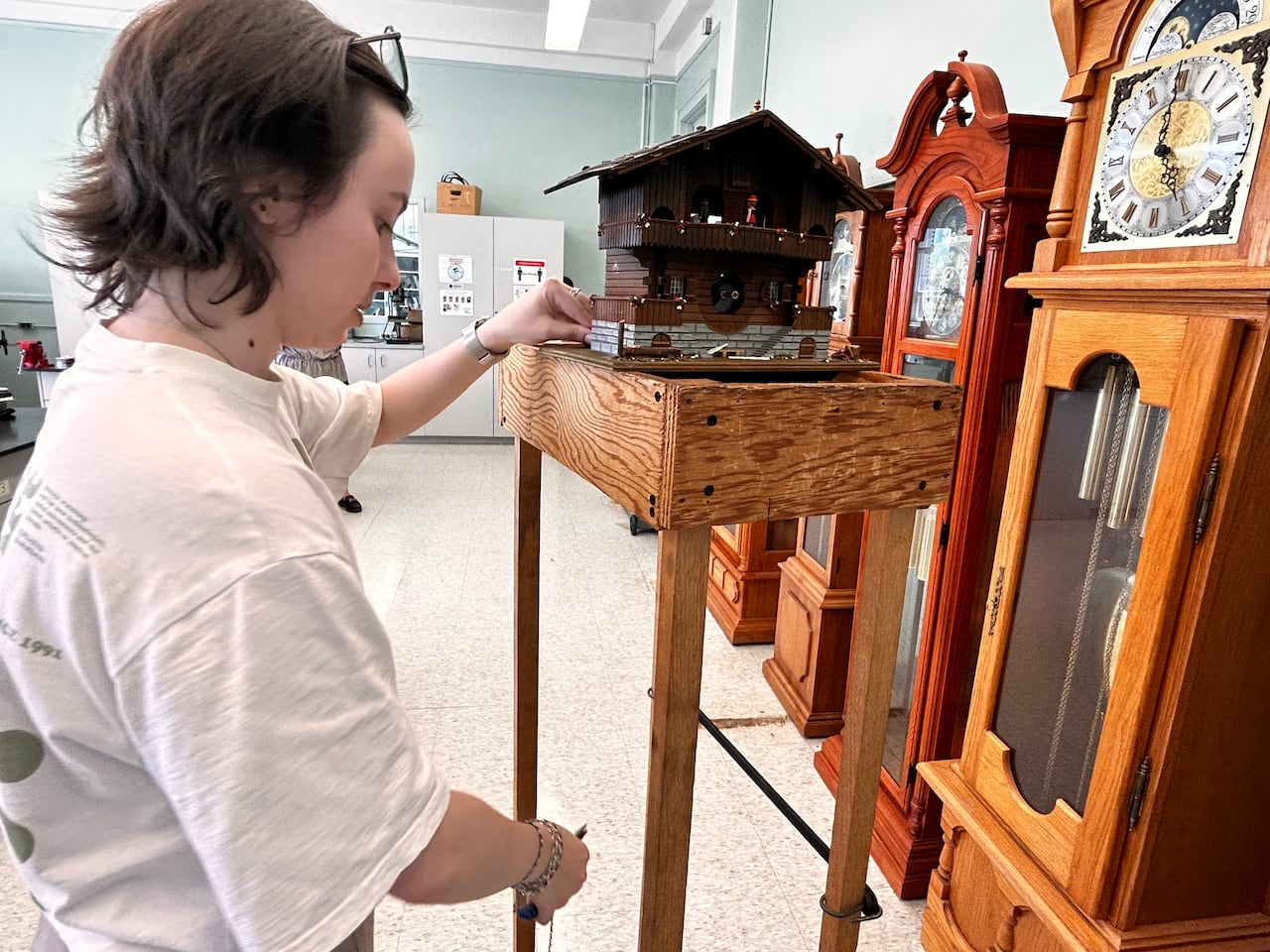 A young woman looks at a clock.