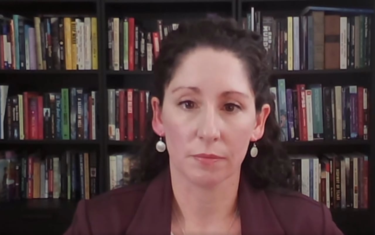 A woman with a bookshelf behind her.