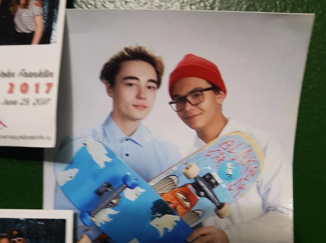 A photo of two teenage boys with skateboards put up in a locker.