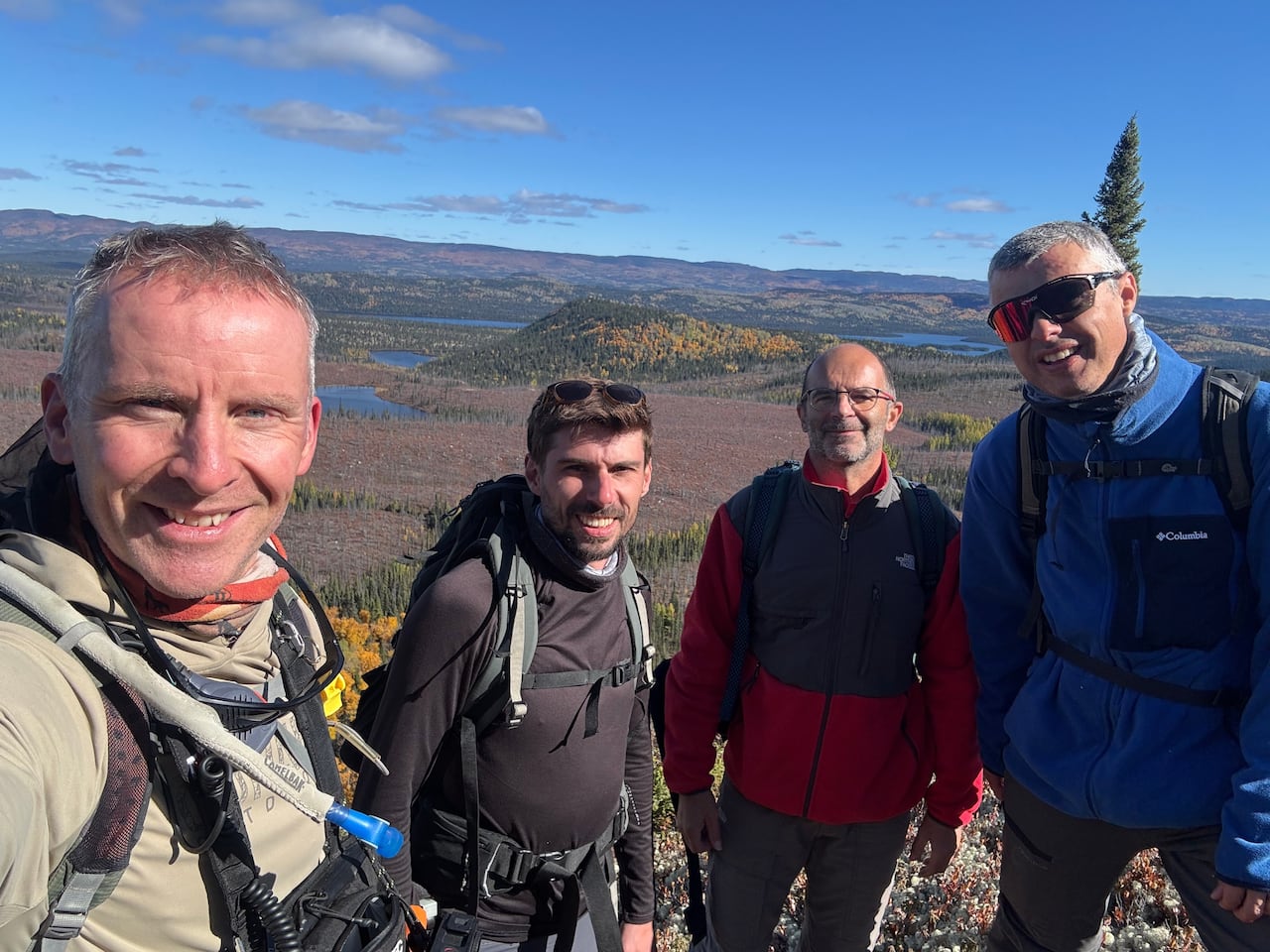 A group of four men standing on a mountain.