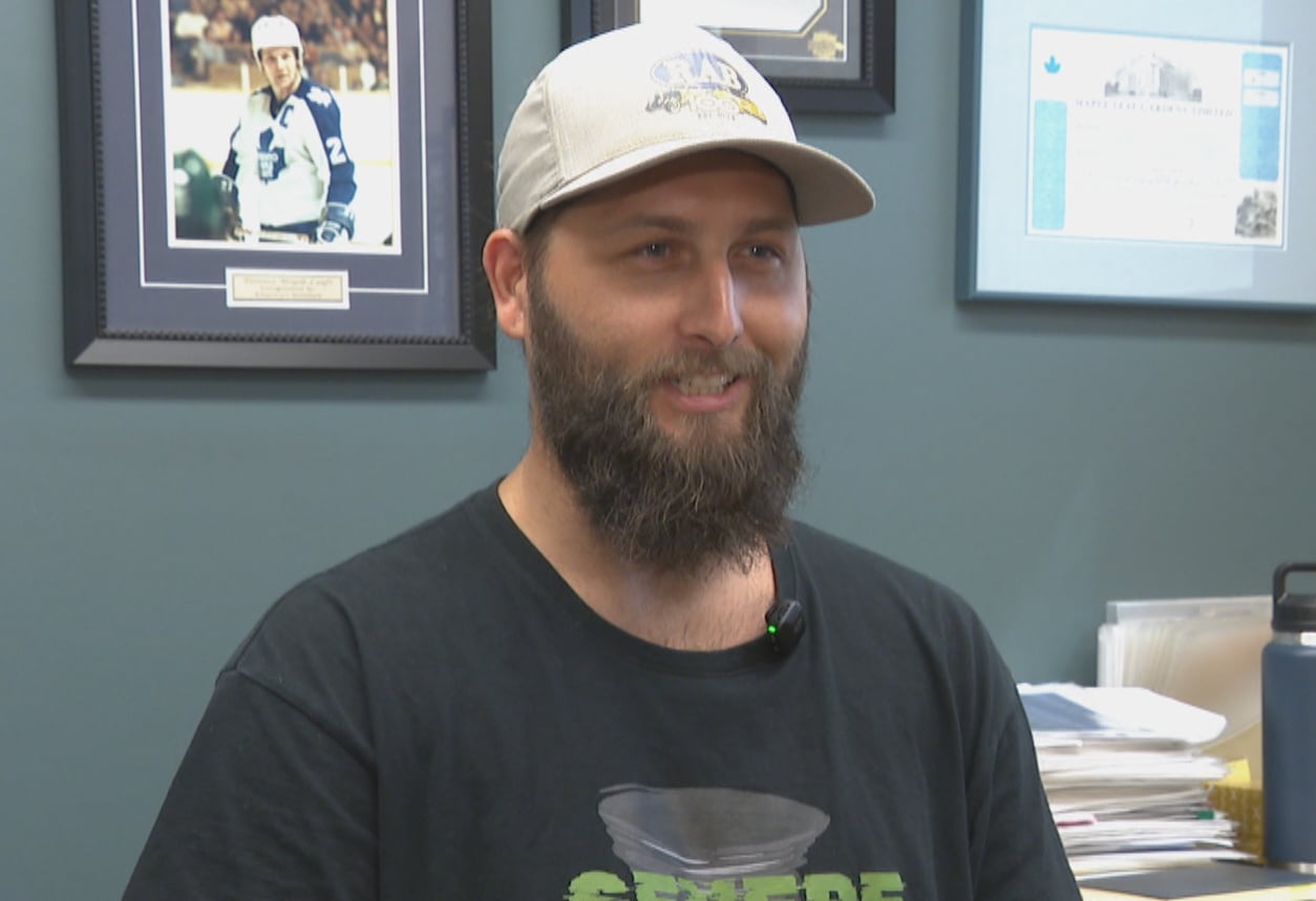 A man with a beard sits in an office.