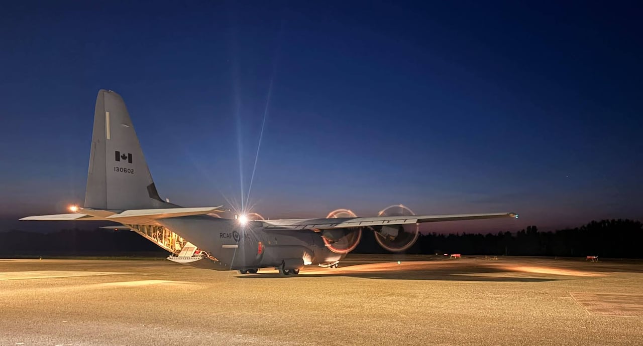 A large military plane is seen on tarmac in the night.