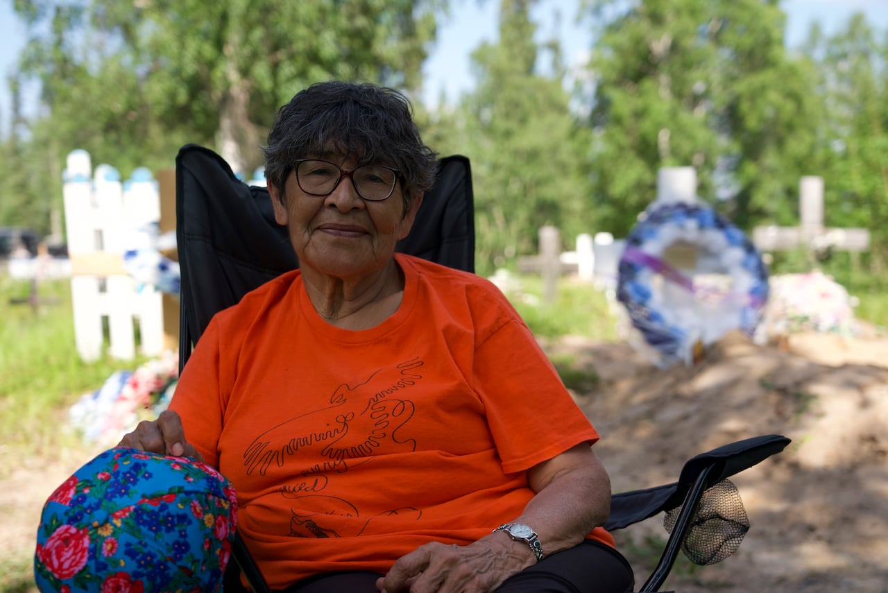 A woman in a lawn chair, with a grave behind her.