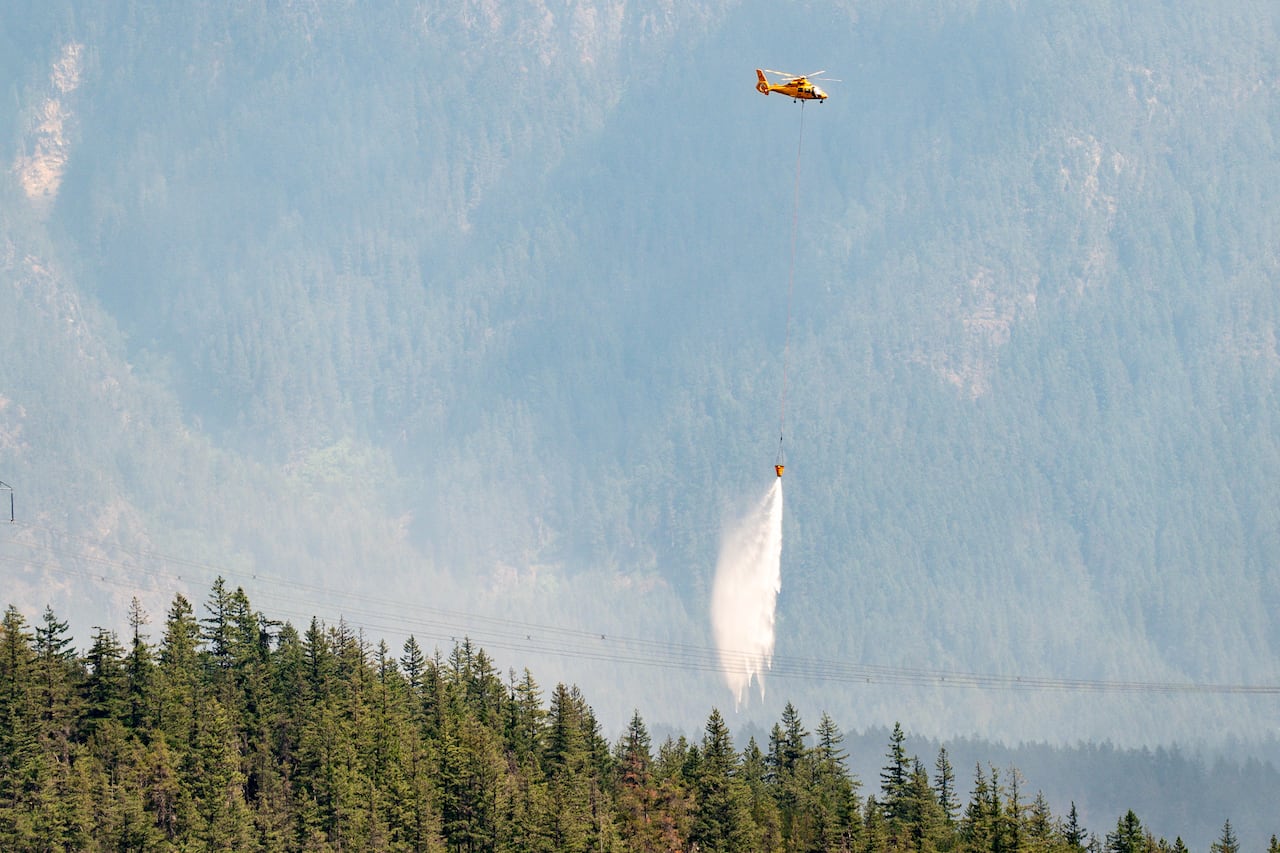 A helicopter can be seen in the distance dropping water while fighting the Signal Hill wildfire in Pemberton.