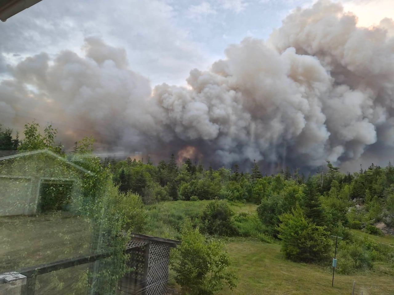 A large forest fire is seen through the window of a home.