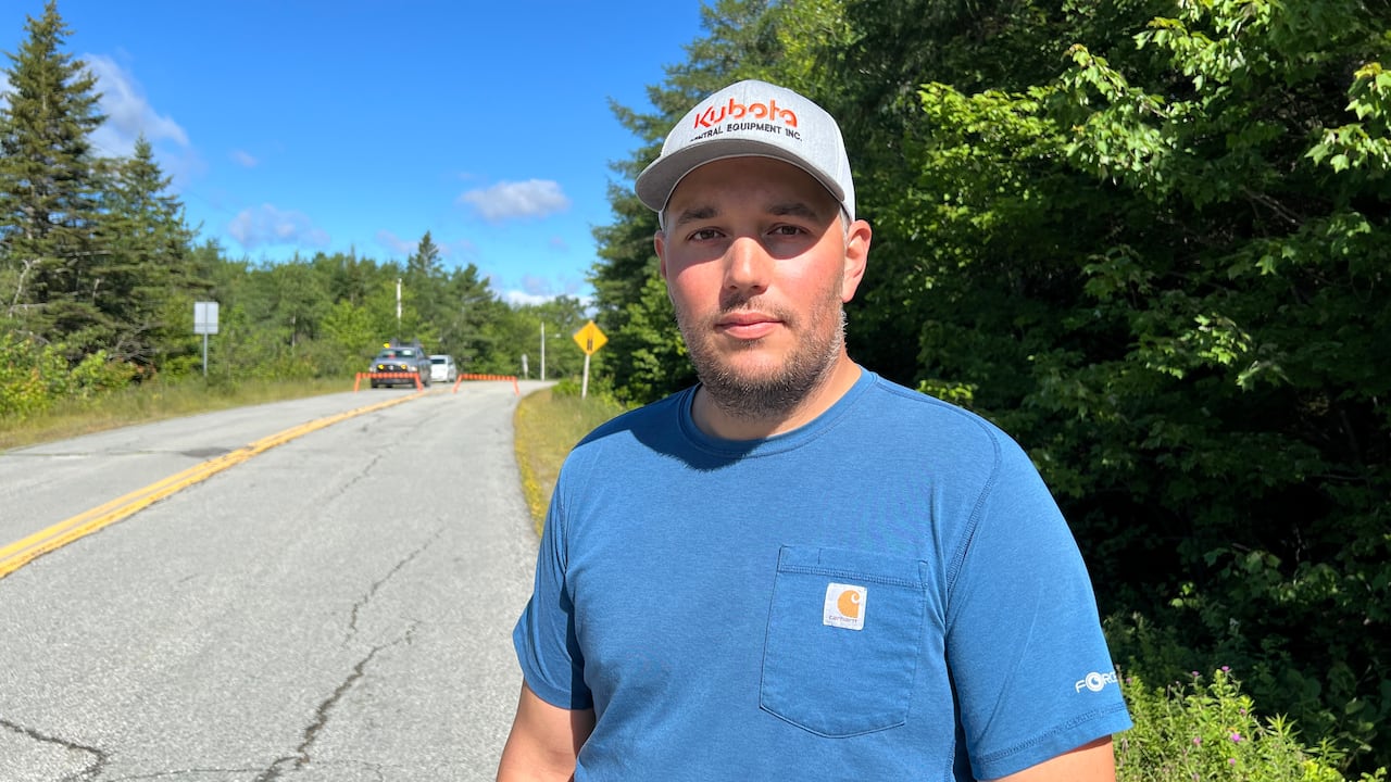 A man in a blue T-shirt is shown along a road.