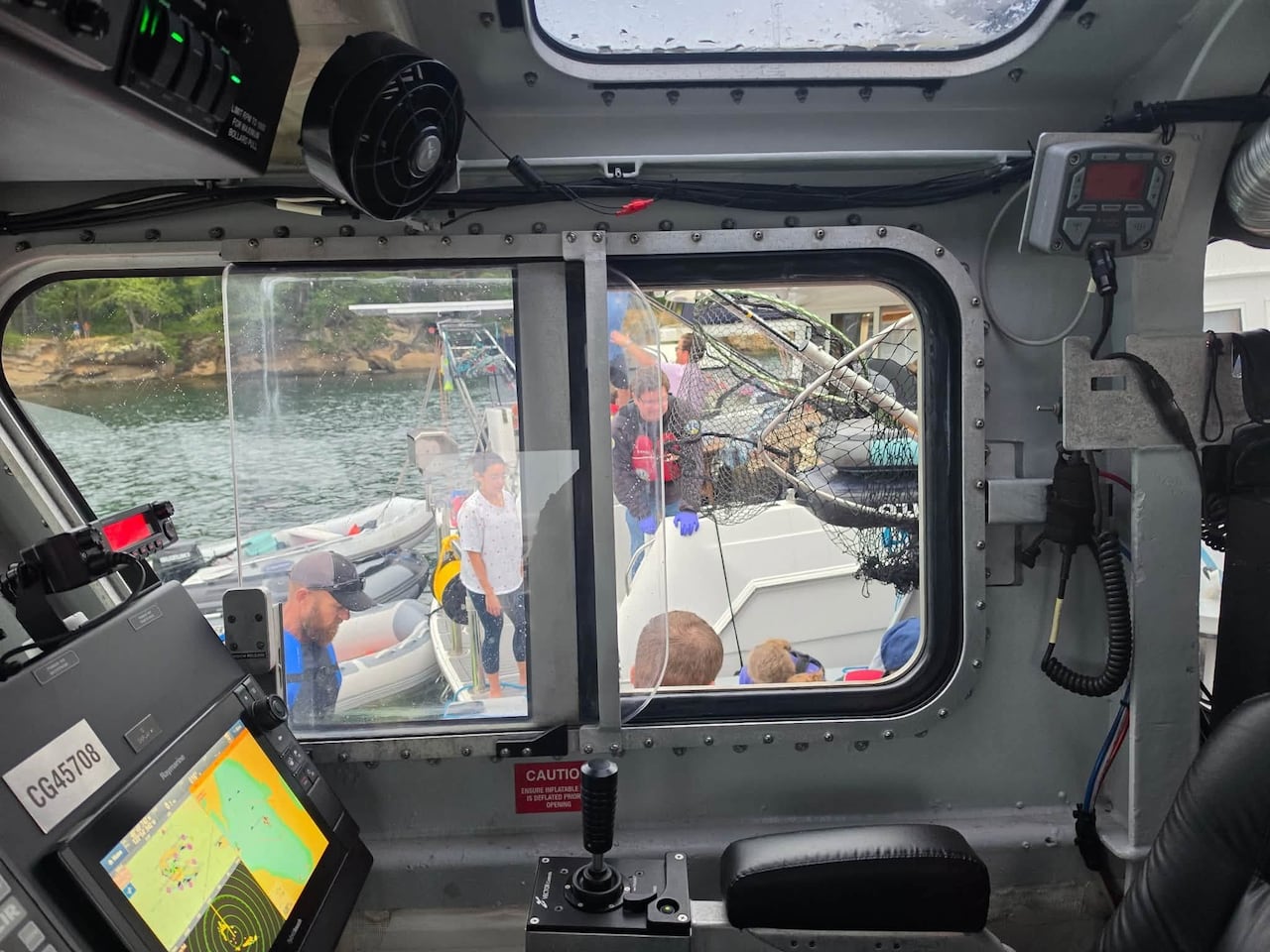 Coast guard officers helping victims on a boat.
