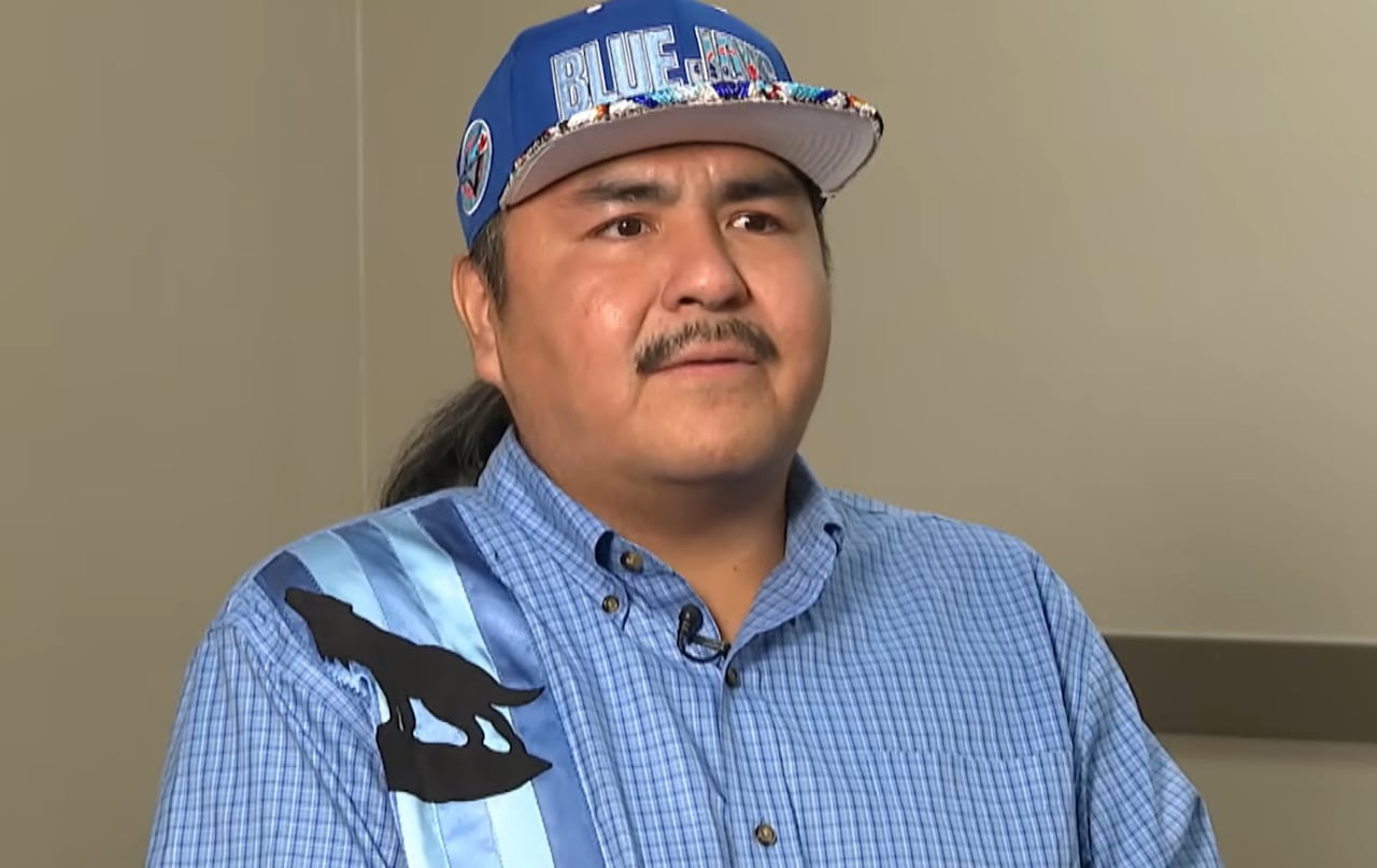 A person is seen in a room. They are wearing a ball cap and a blue shirt.