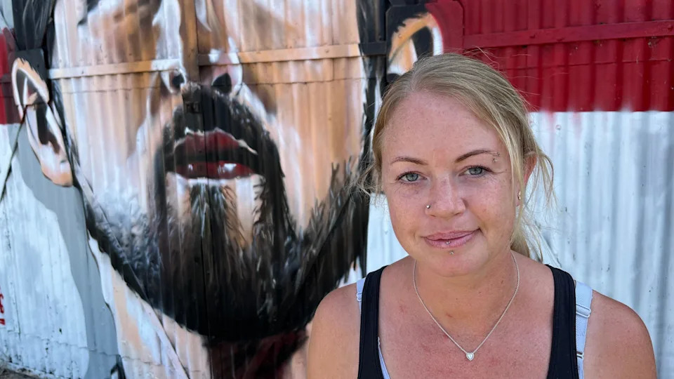 Jade, a woman wearing a black sleeveless top, standing in front of the Kane mural.