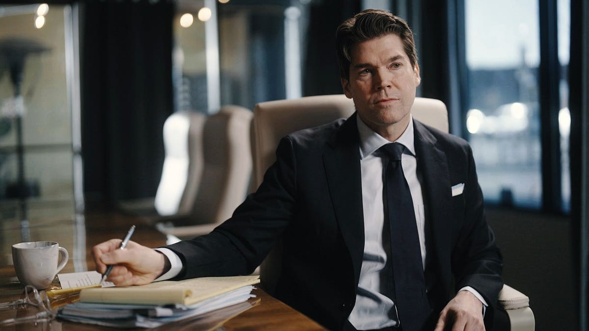 Chris Pixley in a suit sitting at an office.