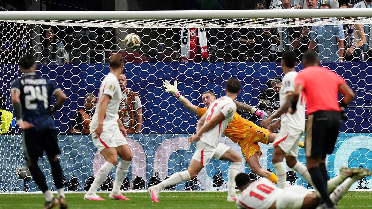 Jordan Pickford dives as Enzo Fernandez shoots in a soccer match.