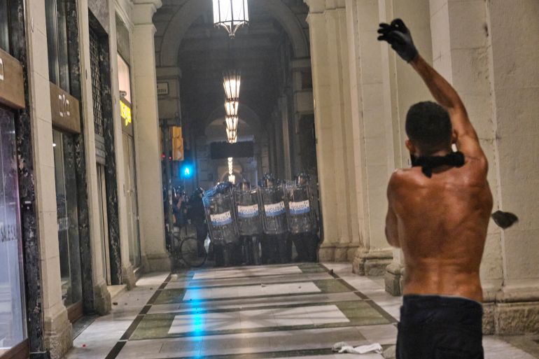 A protester gestures with a raised hand as police officers stand nearby during a demonstration in Bologna following Fakir’s death [Dea Sibilla/Al Jazeera]
