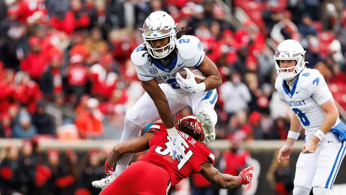 Dante Dowdell of Kentucky hurdling T.J. Quinn Jr. of Louisville during a football game.