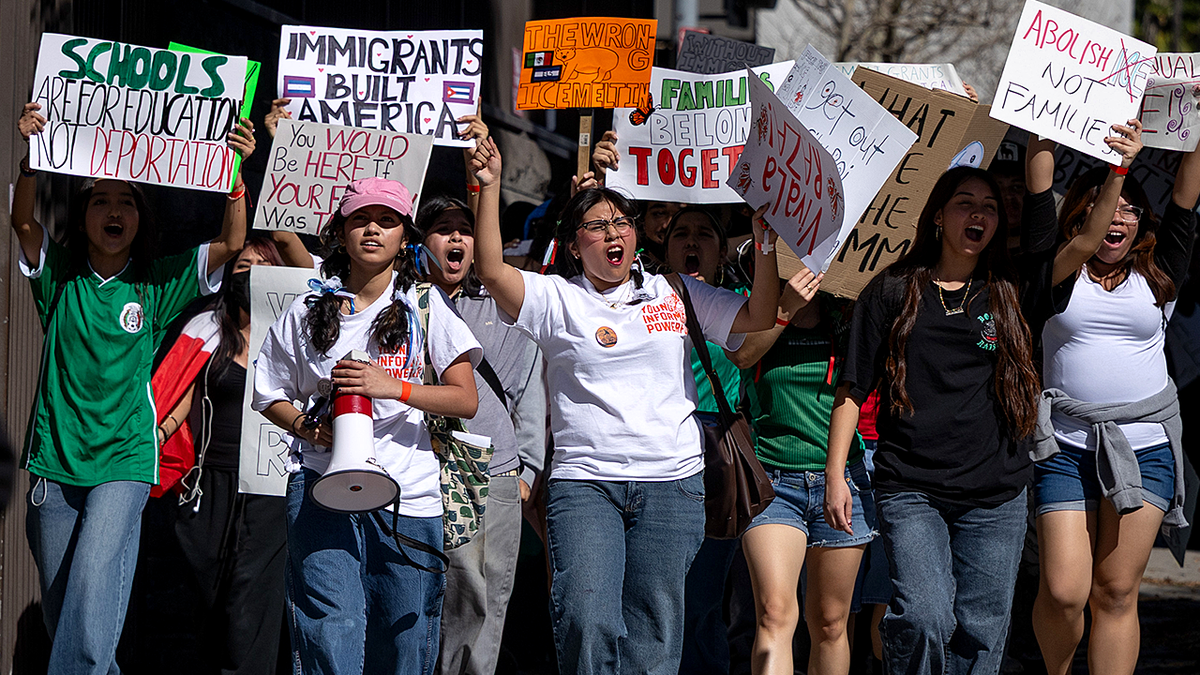 students walk out of class holding anti-ICE signs