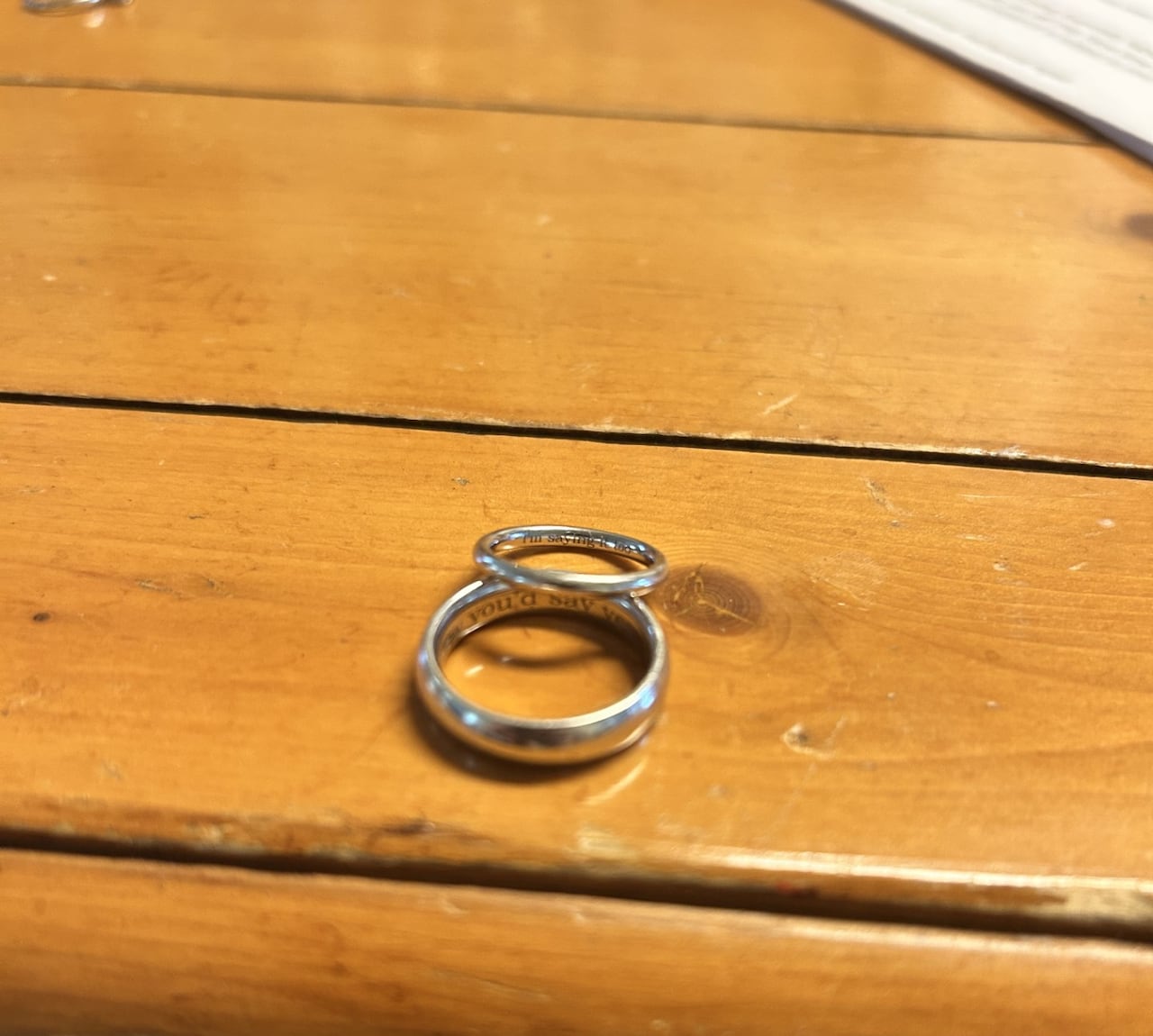 Two rings sit together on a wooden surface.