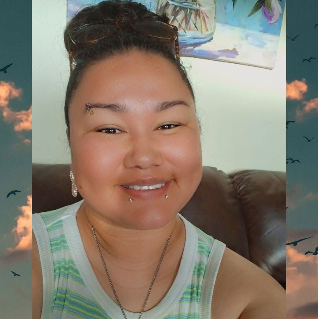 A First Nations woman with a piercing in her eyebrow and two in her lower lip smiles into the camera.